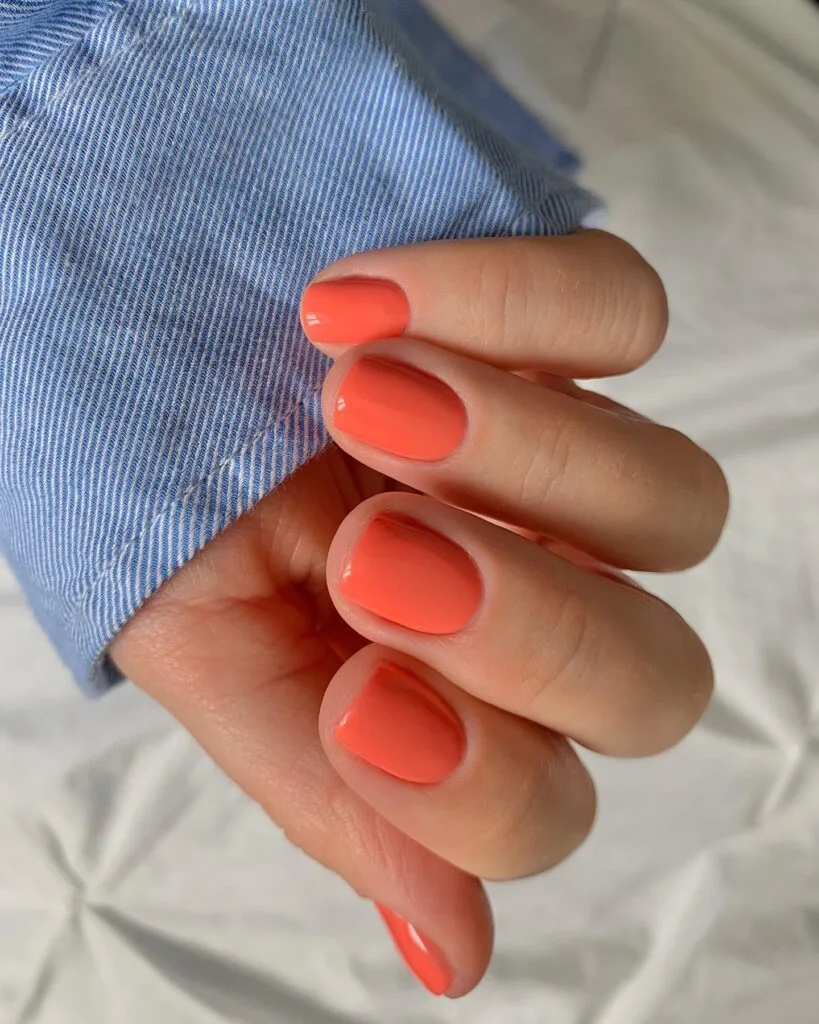 spring nail colors 2026, coral short square nails, glossy finish, denim background