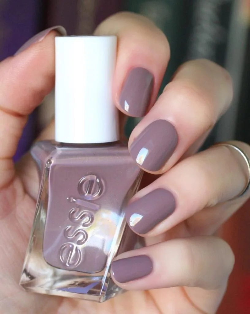 spring nail colors 2026, muted mauve short square nails holding Essie nail polish bottle