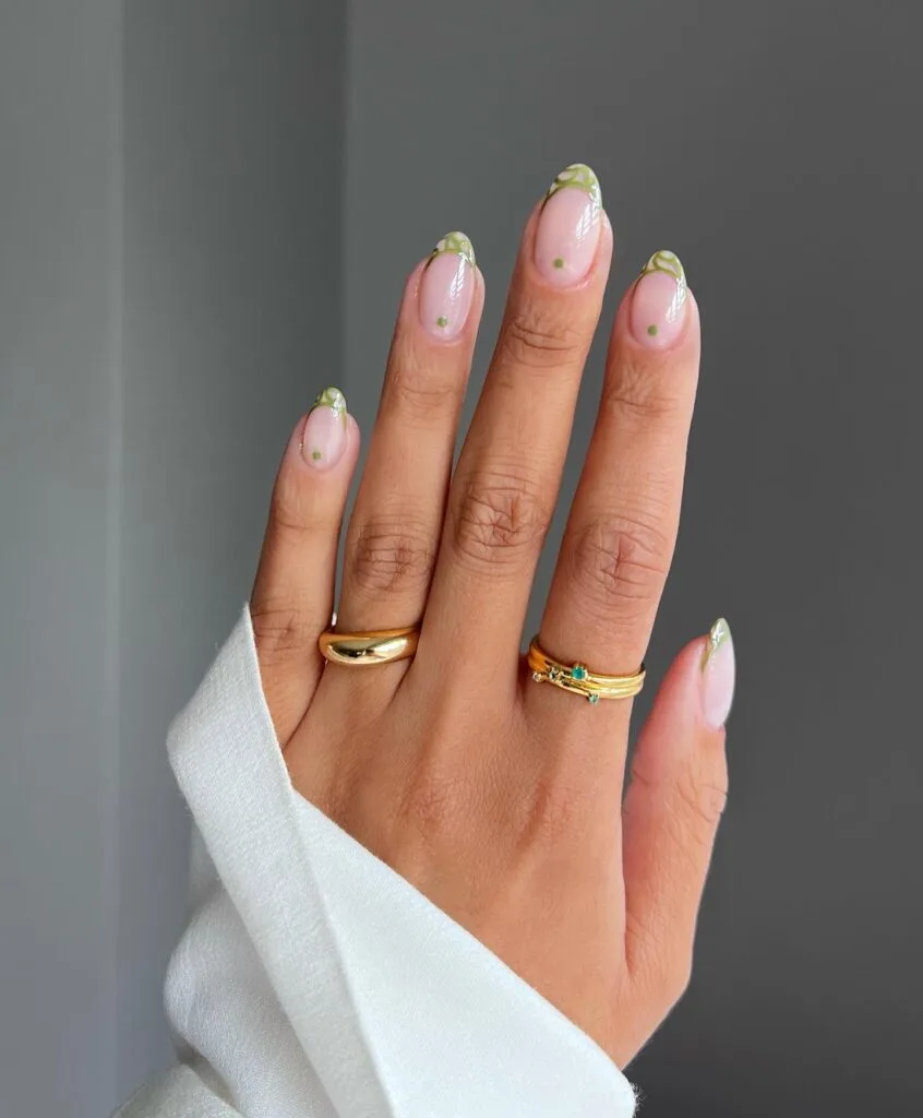 may nails, almond sheer pink nails with olive green French tips, white vine details, and green dot accents
