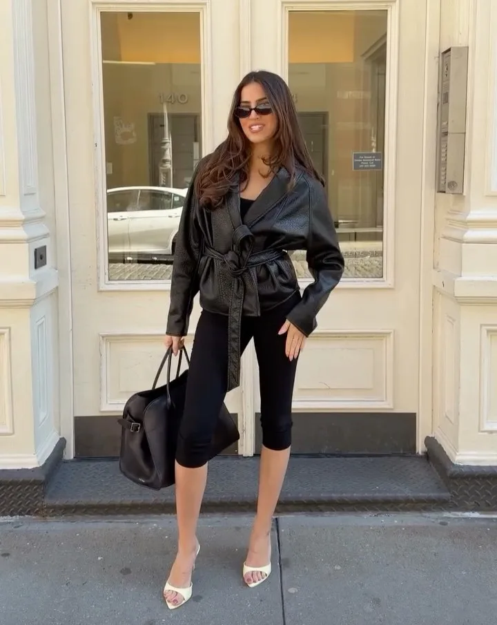 may outfit with black belted leather jacket, black capri pants, cream open-toe mule heels, and black tote bag