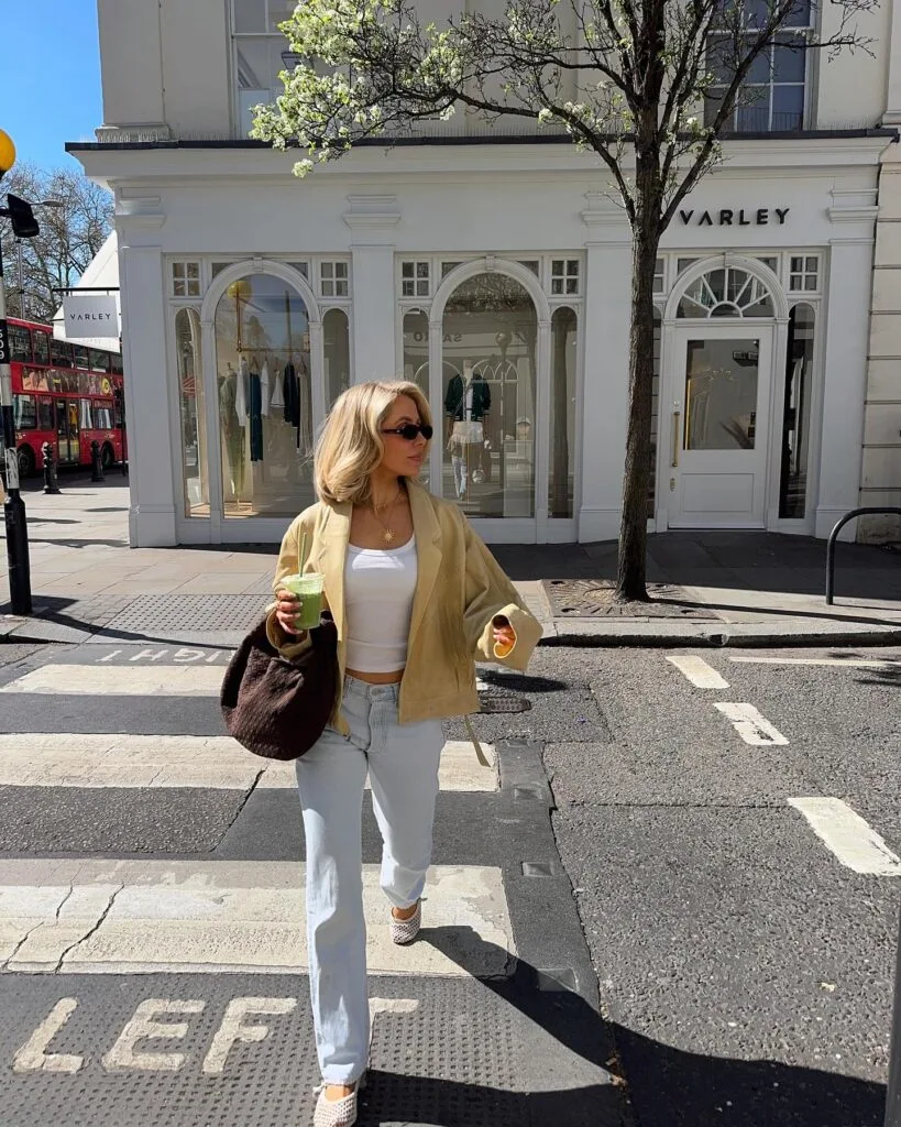 may outfit with tan open-front jacket, white tank top, light wash cuffed jeans, brown woven tote bag, and woven flats