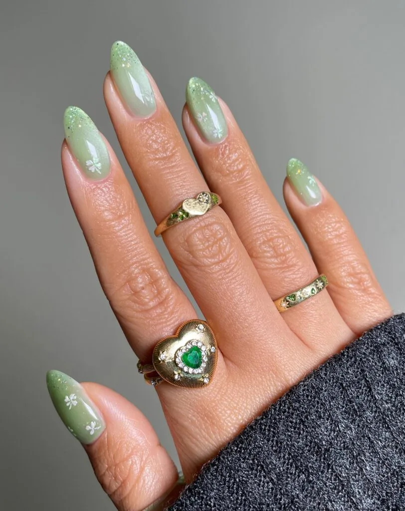 may nails, almond sage green ombre nails with gold glitter and small white floral stamps
