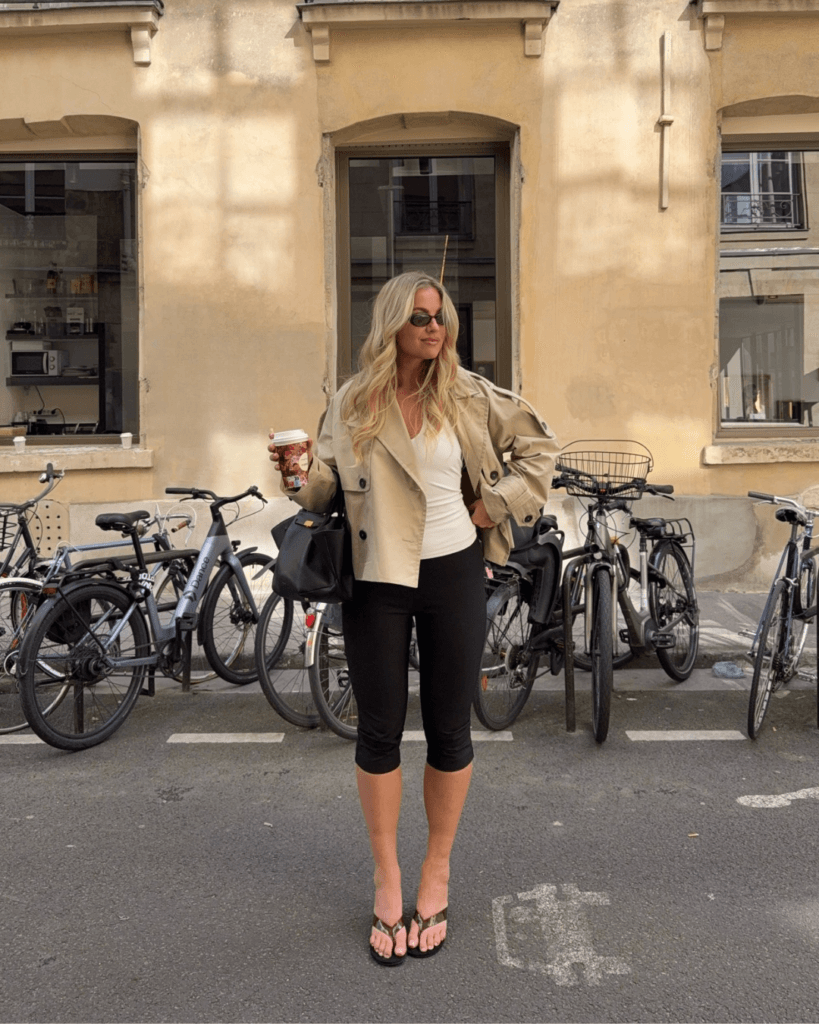 may outfit with beige cropped trench coat, white v-neck top, black capri leggings, and thong sandals
