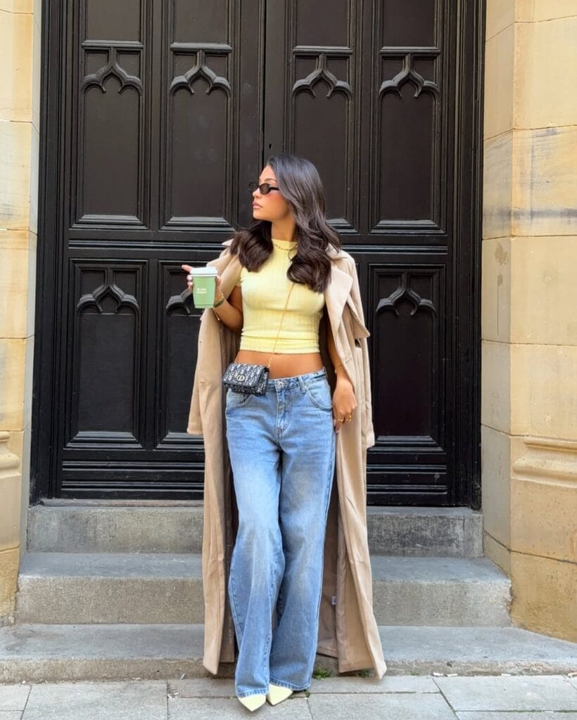 may outfit with yellow crop top, light wash wide-leg jeans, long beige trench coat, and yellow pointed heels
