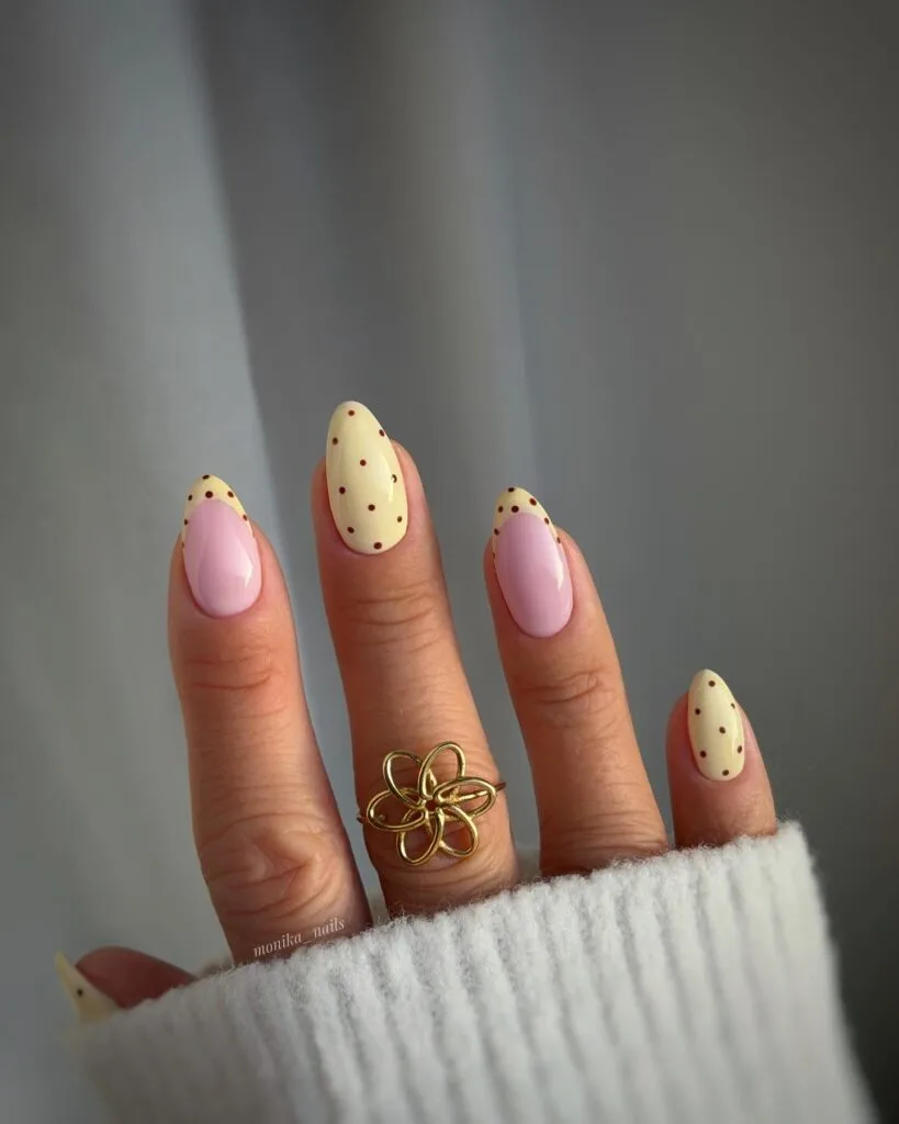 simple spring nails, almond pale yellow French tips with brown polka dots on sheer pink base
