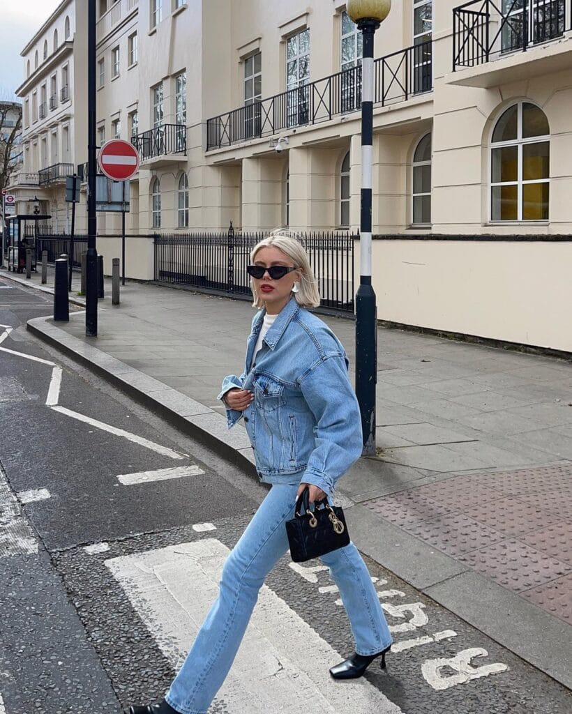 may outfit with oversized light wash denim jacket, white tee, light wash straight-leg jeans, and black mini bag

