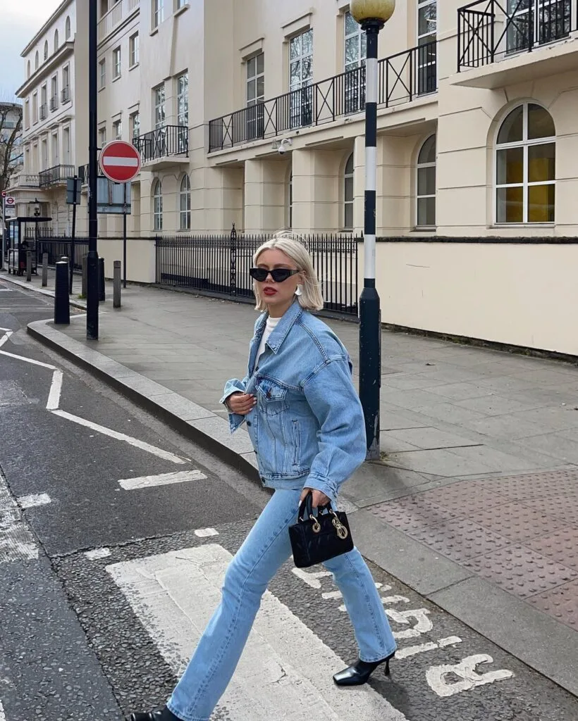 may outfit with oversized light wash denim jacket, white tee, light wash straight-leg jeans, and black mini bag
