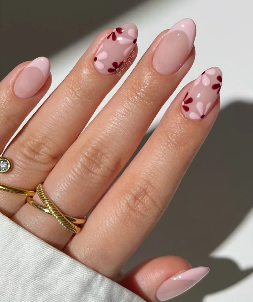 may nails, almond nude pink nails with burgundy and blush floral petal accents on sheer base
