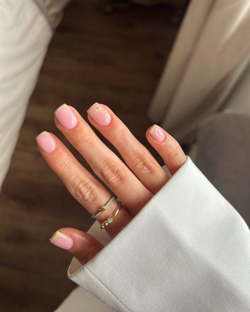 simple spring nails, short square pink nails with light green French tips and small daisy accent