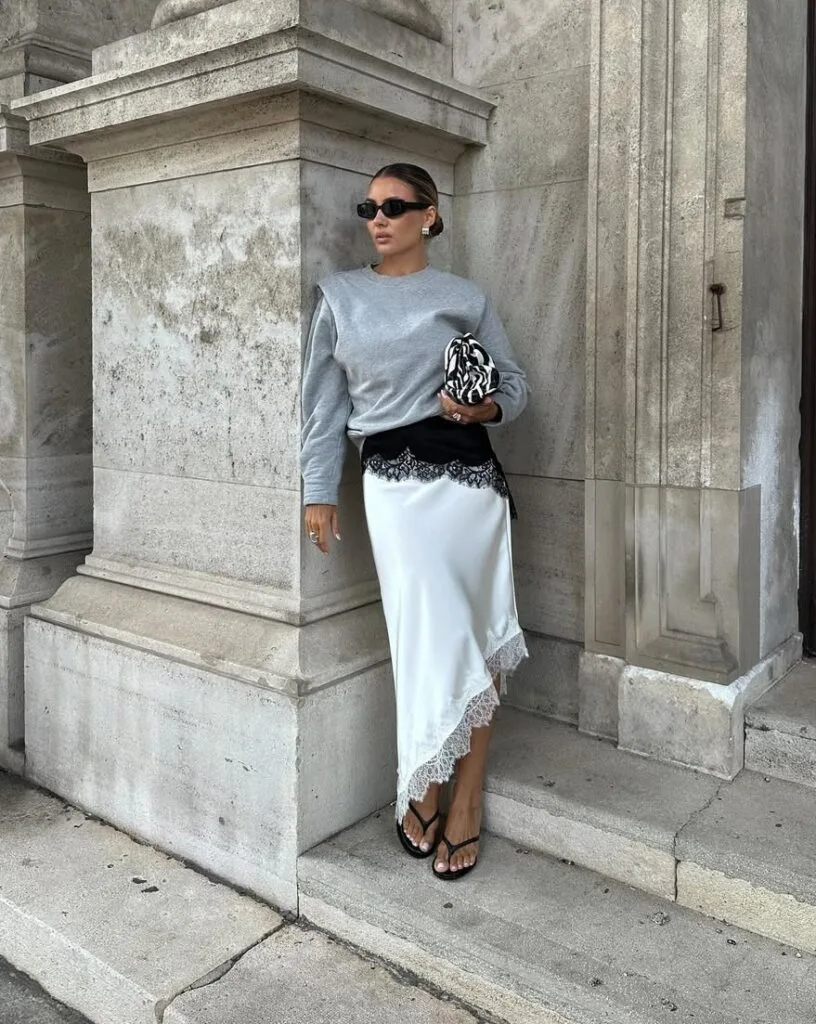 spring fashion trends 2026, white satin midi skirt with lace hem layered under grey sweatshirt