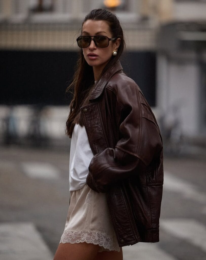 spring fashion trends 2026, cream lace-trimmed mini dress under brown leather jacke