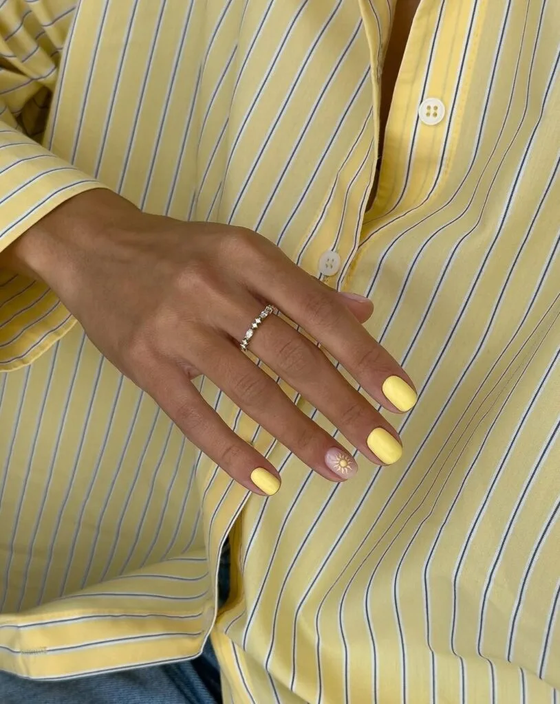 june nail color trends, pastel yellow short square nails with small sun accent nail art