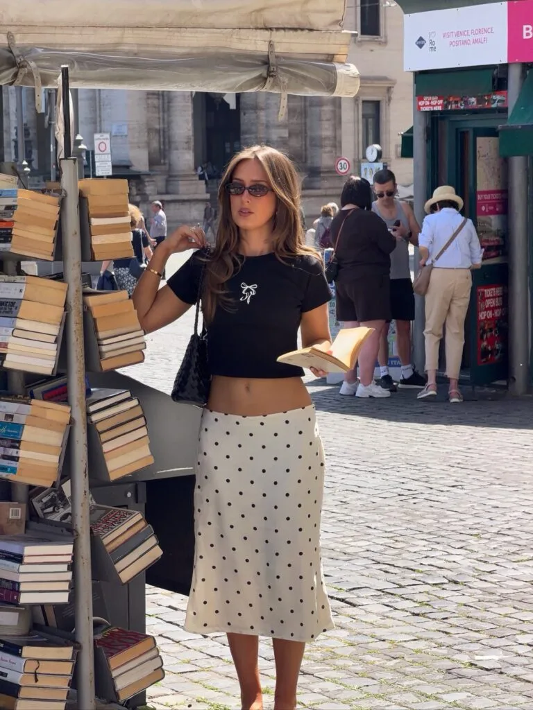 summer fashion trends 2026, cream midi skirt with black polka dots, black crop tee, and sunglasses