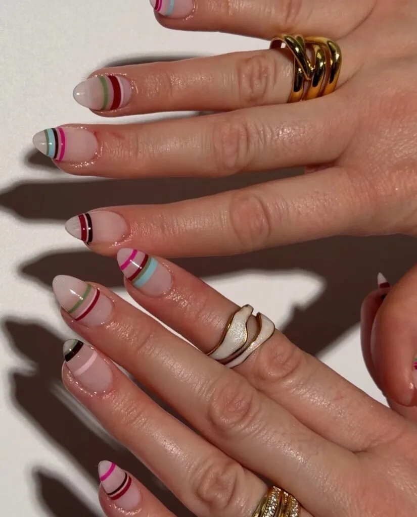 summer nail trends 2026, multicolor thin stripe nails on sheer base with gold rings