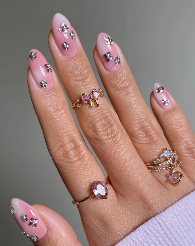 summer nail trends 2026, pink almond nails with scattered multicolor gems in gold settings