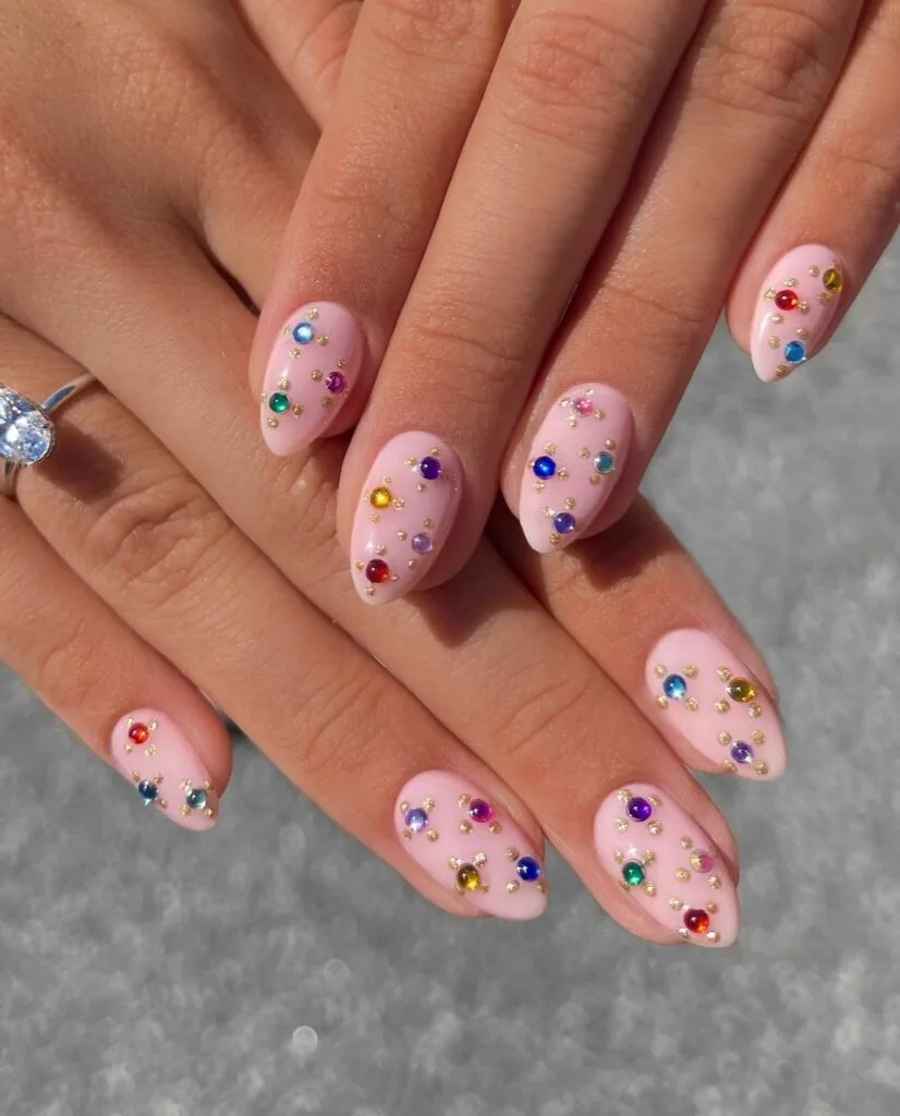 summer nail trends 2026, sheer pink almond nails with silver flower-shaped gem clusters