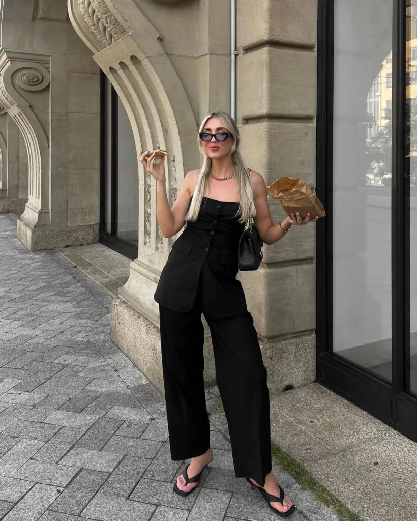 june outfit with black strapless button-front vest, black wide-leg trousers, black flip-flops, and chain necklace
