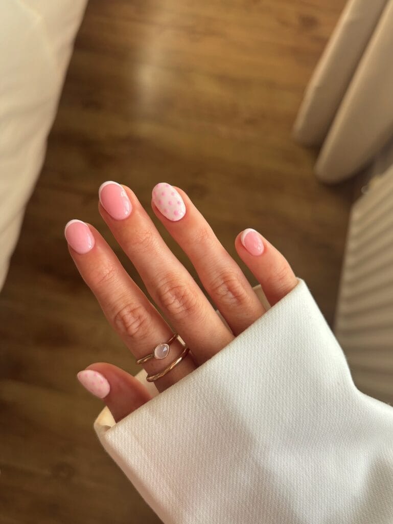  neutral summer nails, short almond pink French tip nails with pink polka dot accent nails on sheer base
