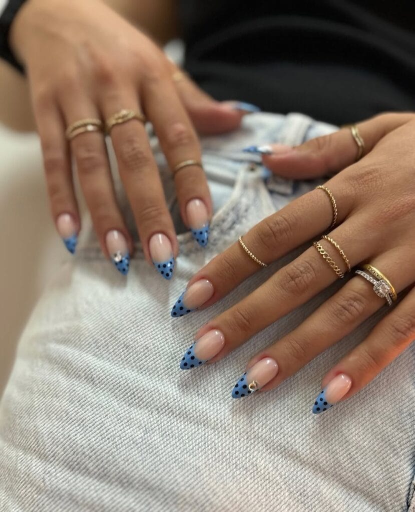 July nail ideas, nude almond nails with cornflower blue polka dot French tips and tiny gem accent
