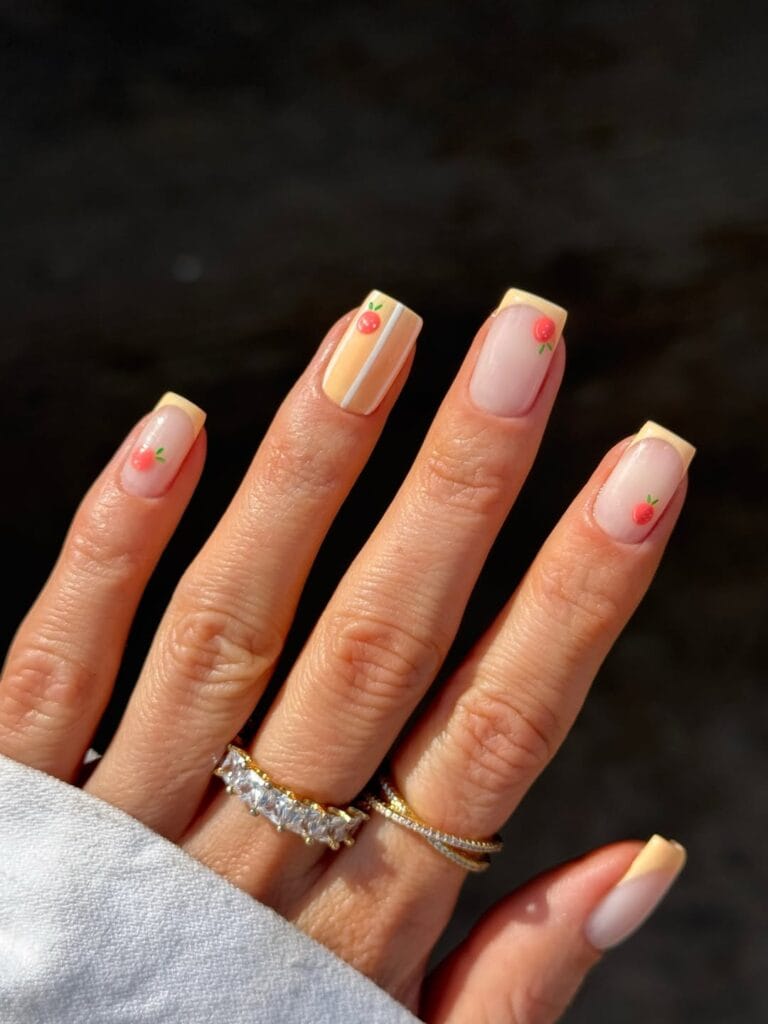 July nail ideas, milky short square nails with butter yellow French tips tiny orange fruit and stripe accent
