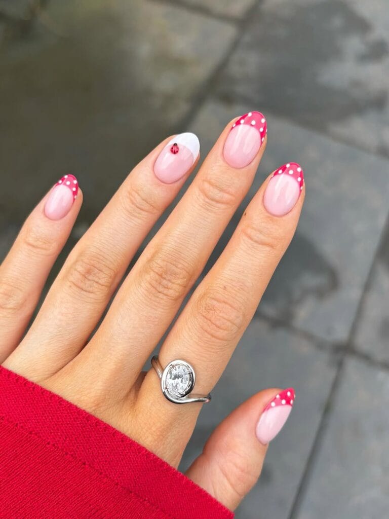 June nail ideas, pink almond nails with red polka dot French tips and ladybug accent nail