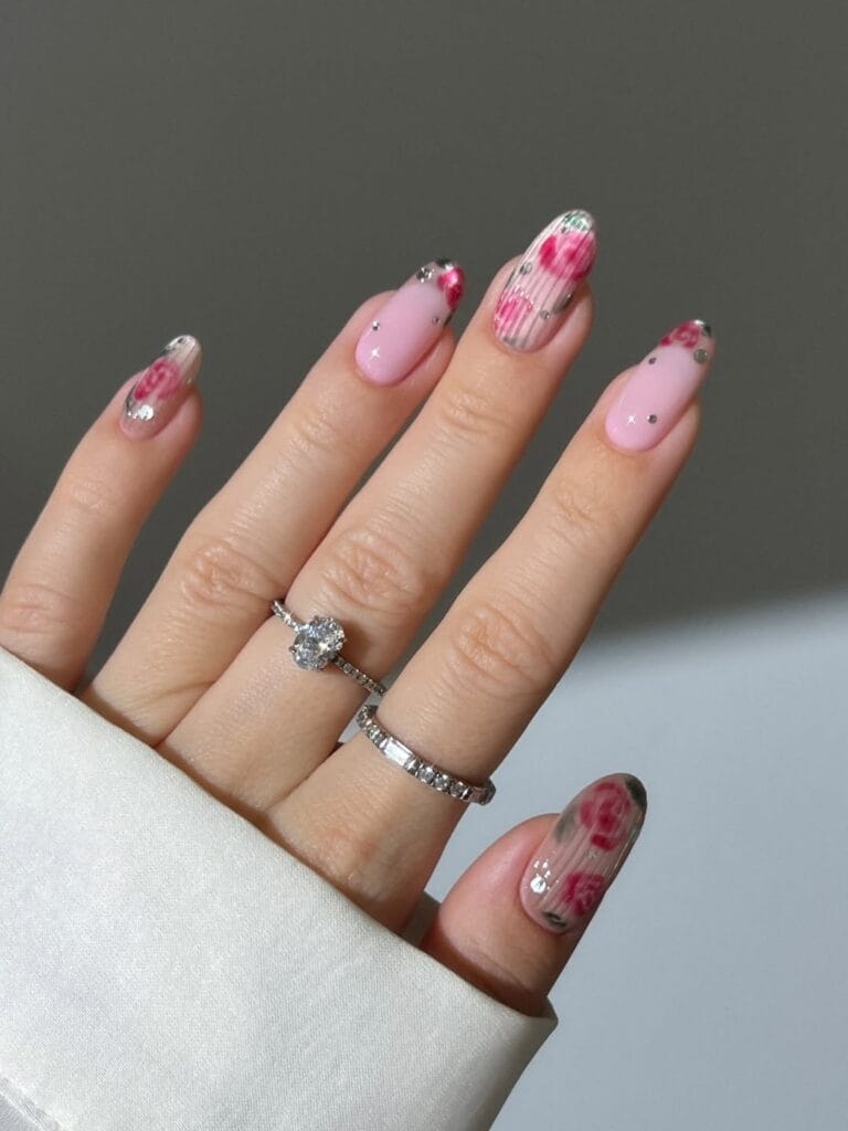 July nail ideas, milky pink almond nails with vintage red rose art silver chrome edges and tiny gems
