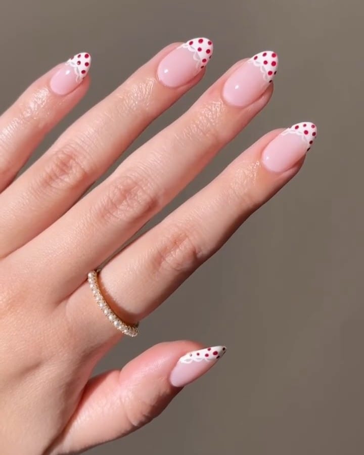 summer nail trends 2026, pink almond nails with red polka dot French tips and scalloped edge