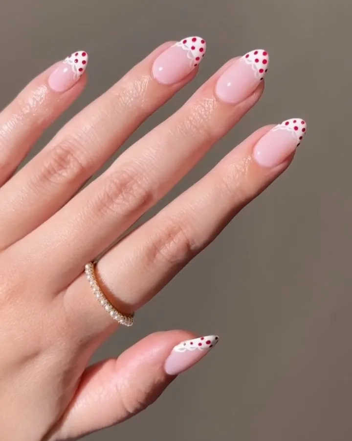 summer nail trends 2026, pink almond nails with red polka dot French tips and scalloped edge