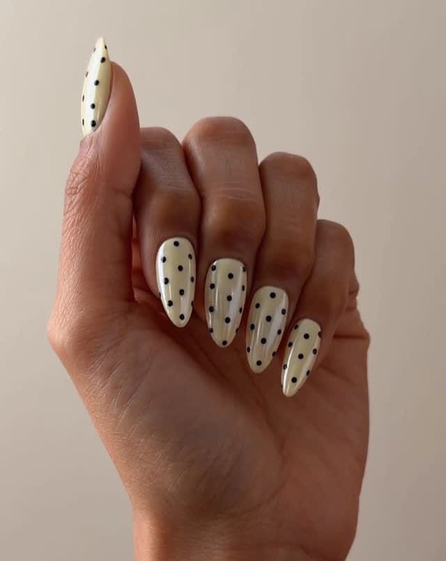 summer nail trends 2026, cream almond nails with small black polka dots all over