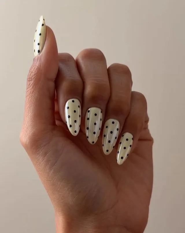 summer nail trends 2026, cream almond nails with small black polka dots all over