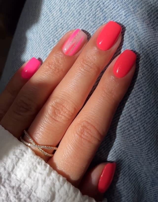June nail ideas, coral and hot pink short square nails with brushstroke accent nail
