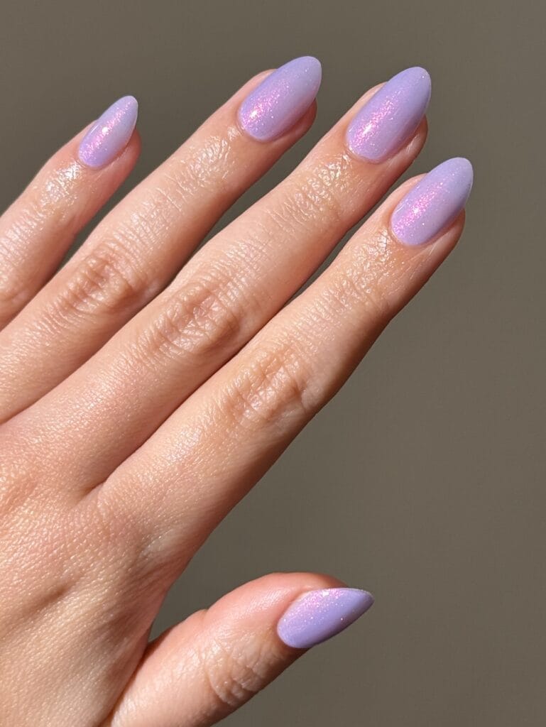 June nail ideas, lilac shimmer almond nails with pink glitter finish

