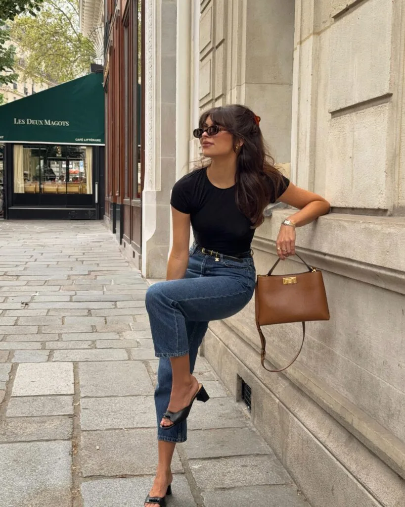 june outfit with black fitted tee, medium wash cropped jeans, black heeled mule sandals, and cognac structured bag
