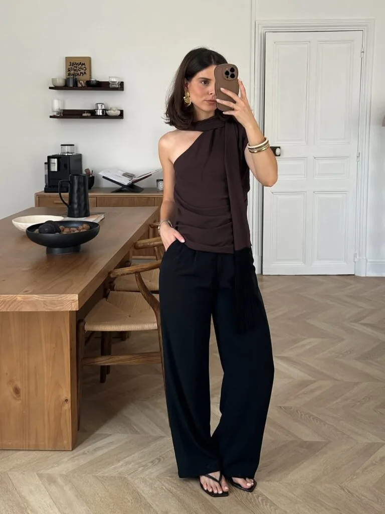 summer outfit with brown draped one-shoulder top, black wide-leg trousers, black heeled thong sandals, and gold jewelry