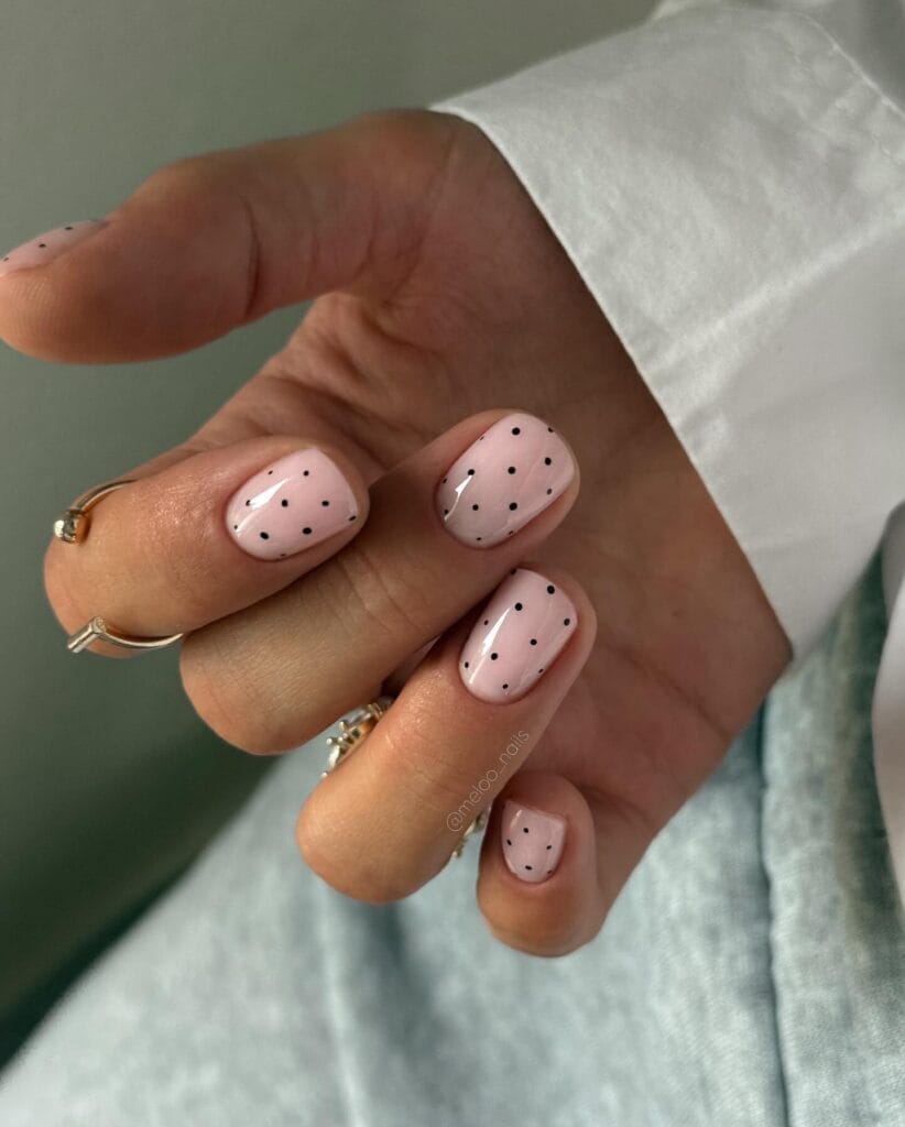 neutral summer nails, short square blush pink nails with scattered black polka dot accents
