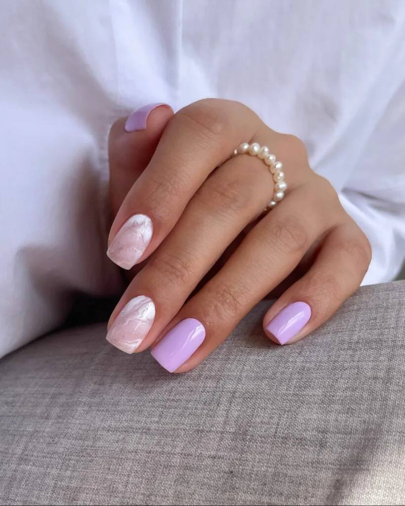 June nail ideas, lilac glossy short square nails with white marble swirl accent nails and glitter speckles
