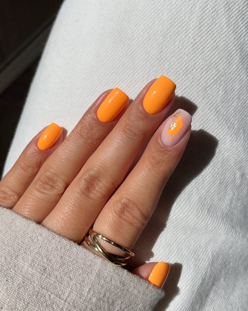 July nail ideas, bright tangerine orange short square nails with milky accent nail and gold flecks
