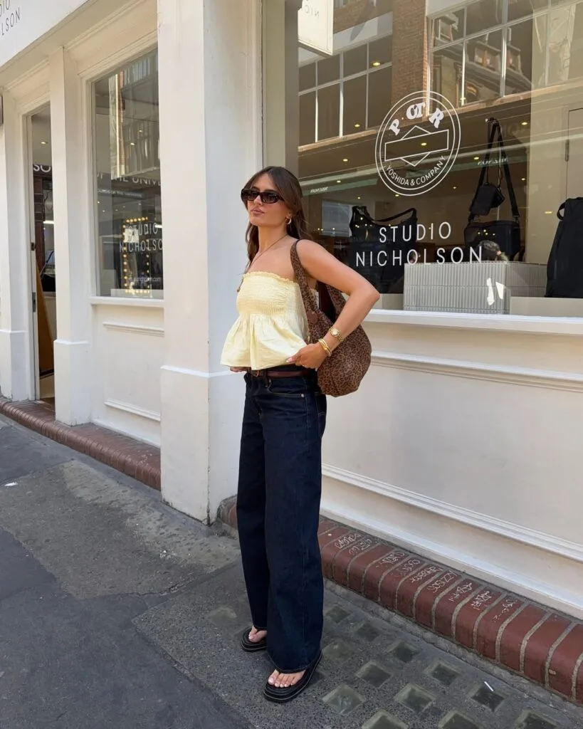 june outfit with yellow smocked strapless top, dark wash wide-leg jeans, platform sandals, and leopard bag
