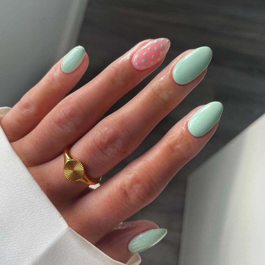 June nail ideas, glossy mint green almond nails with pink polka dot accent nail
