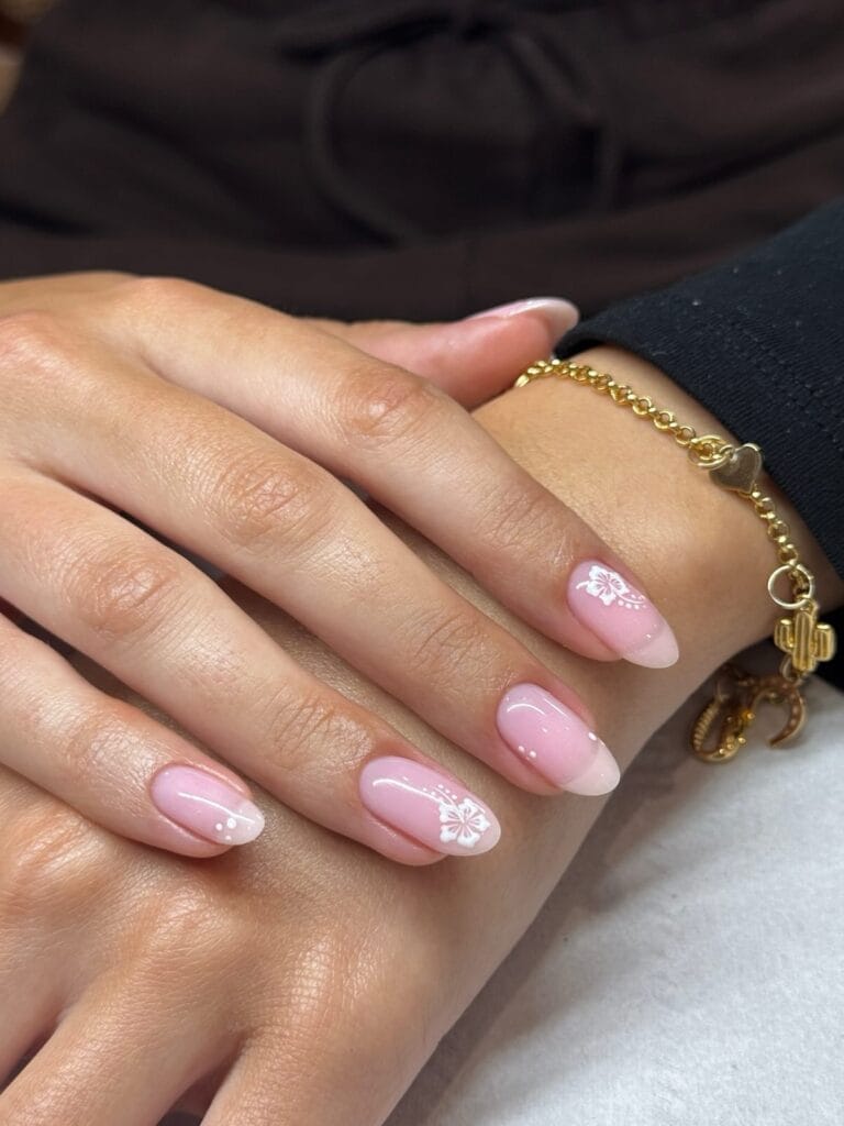 neutral summer nails, short round pink nails with French fade and white hibiscus flower stamp accents
