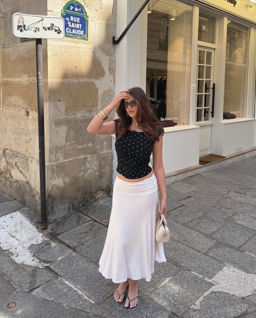 summer outfit with black polka dot cap-sleeve top, white fold-over maxi skirt, and thong sandals
