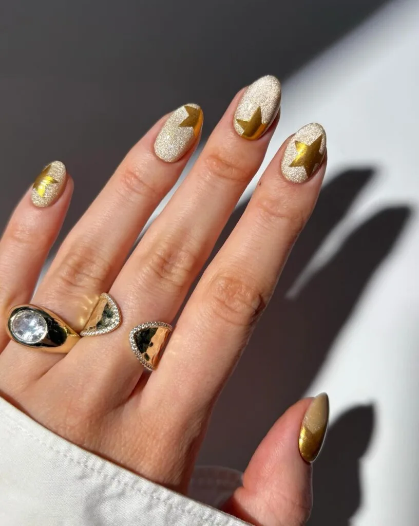 july nail colors, shimmery champagne almond nails with metallic gold star accents