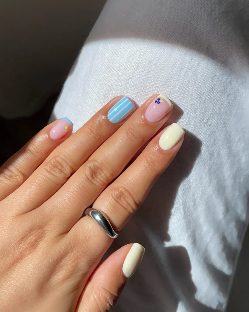 summer nails, short square pastel mix with blue stripes, cream solids, and rhinestone blueberry accent
