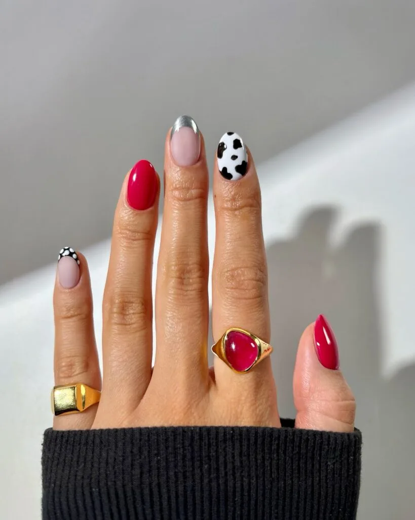 august nails, oval cherry red nails with cow print accent, silver chrome French tip, and dotted black tip
