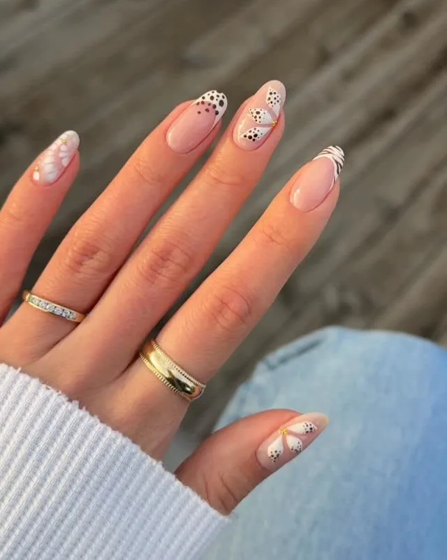 summer nails, almond milky nails with white petal art, dotted French tips, and zebra stripe accent

