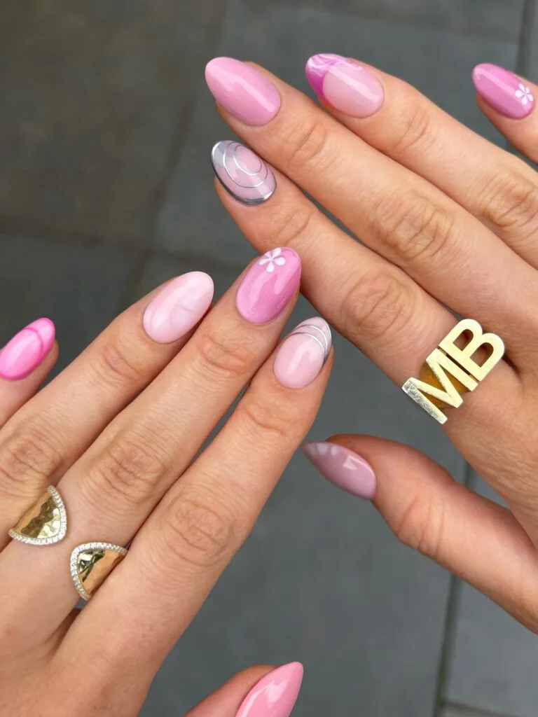summer nails, almond mix and match pink nails with swirl French, silver line art, and white flower accents
