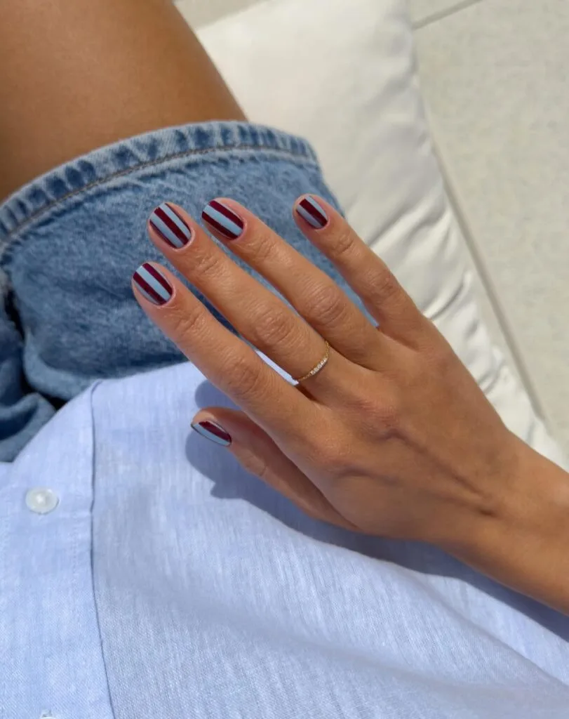 august nails, short powder blue nails with burgundy vertical stripes
