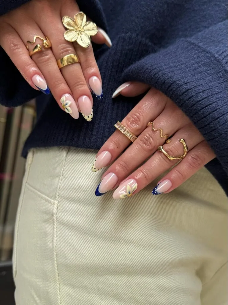 summer nails, long almond navy blue French tips with polka dots and cream flower accent nails
