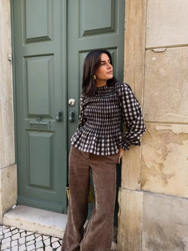 Woman in a gingham peplum top and brown corduroy pants for an autumn outfit.