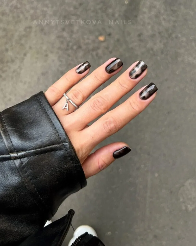Short square fall nails with glossy black polish and smoky silver swirls.
